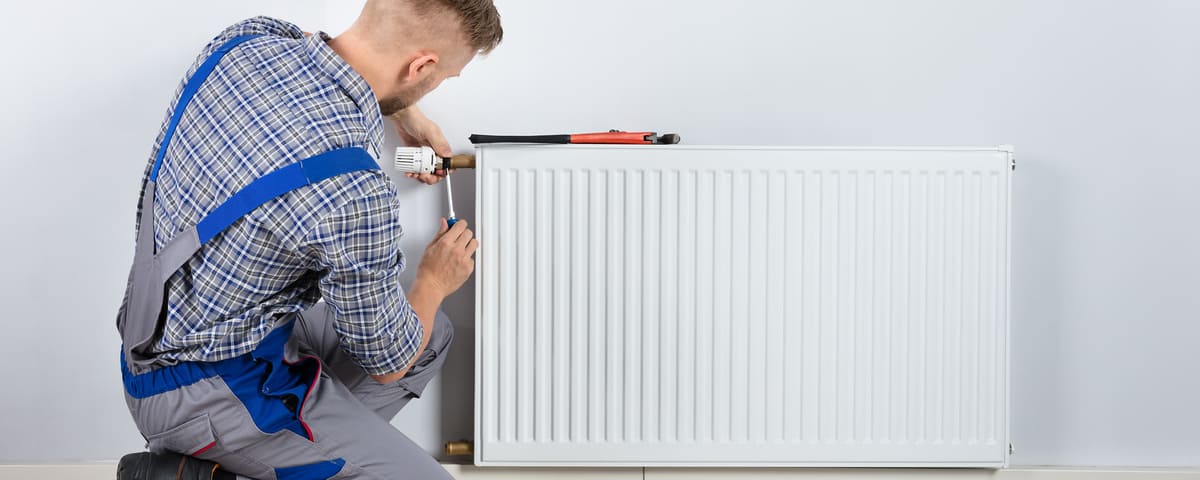 Plombier qui répare un radiateur