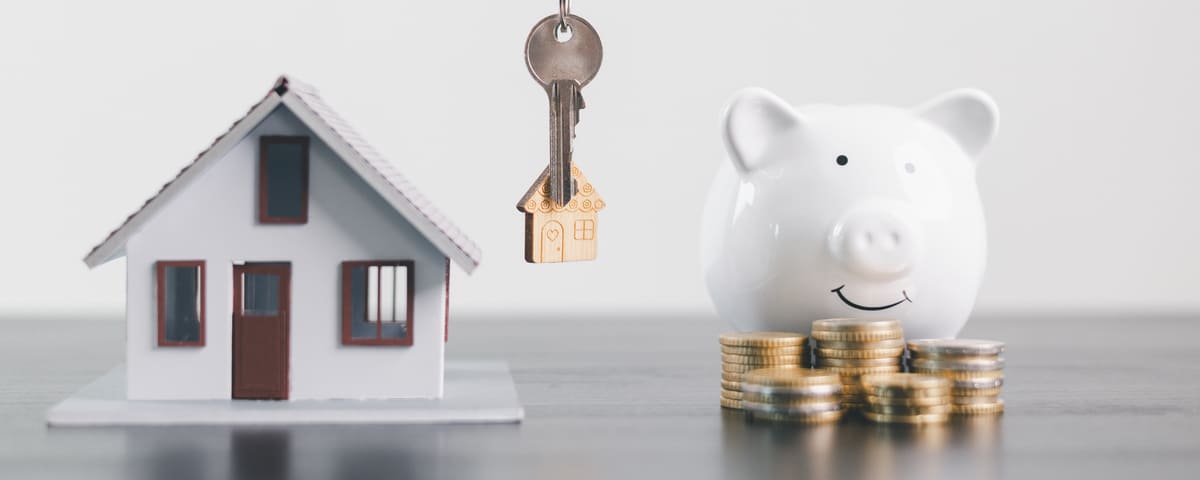 Un modèle maison, une tirelire et des pièces de monnaie