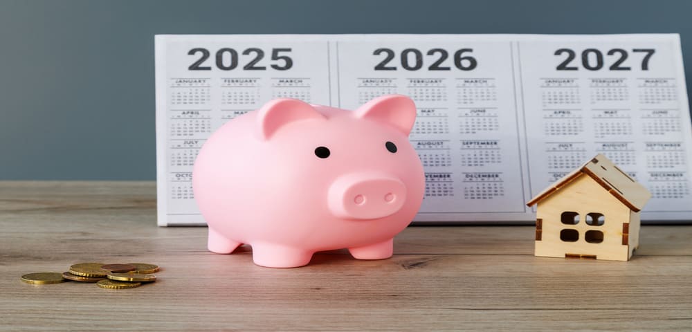  Une tirelire en forme de cochon, une pile de pièces de monnaie et une petite maison en bois, avec un calendrier 