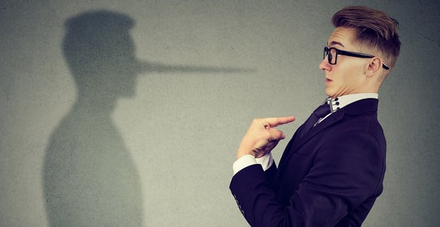 Un homme en costume pointe vers lui-même pendant que son ombre projette un long nez évoquant Pinocchio, symbole du mensonge.